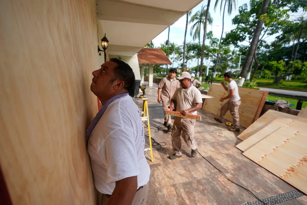 Workers board up windows outside a building.